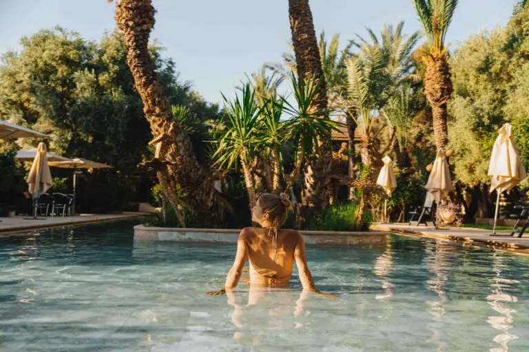 Femme dans une piscine entourée de palmiers