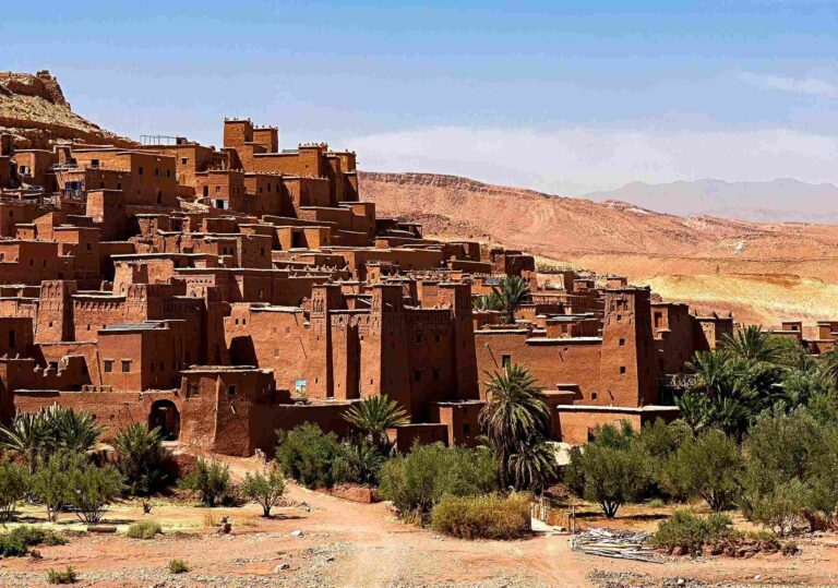 Vue d’Ait Ben Haddou au Maroc, avec ses célèbres kasbahs en terre et des palmiers en premier plan