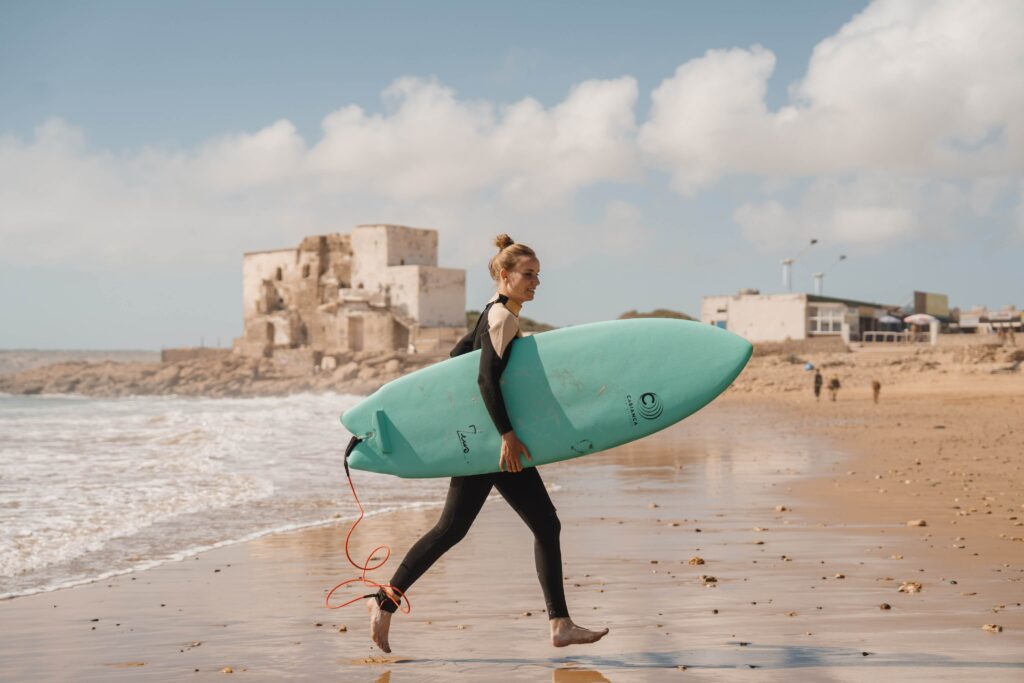 Surfeuse qui marche sur la plage